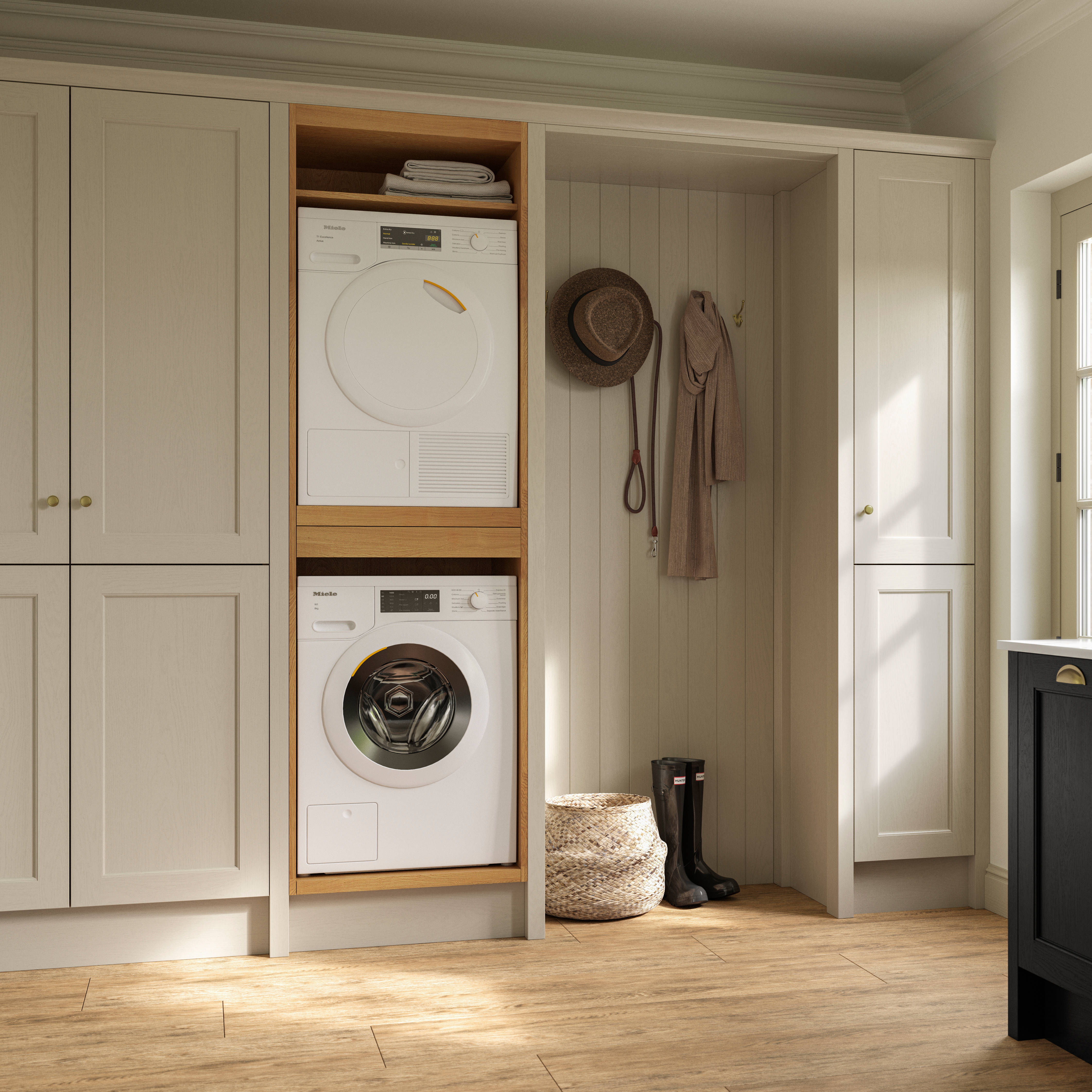 Utility room with Traditional Shaker-style tactile woodgrain Ludlow French Clay cabinets, washing machine and tumble dryer, Ludlow Sumi Black kitchen with brass accessories, Amtico oak stripwood vinyl flooring.