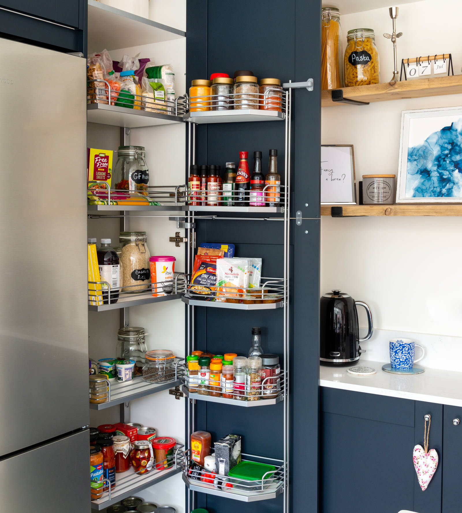 Opened tall larder cabinet with pull-out shelves and shelves on the inside of the door.