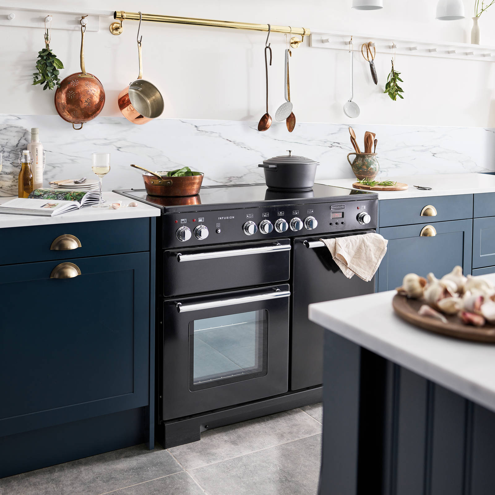Dunham voyage kitchen with white marbled worktop and backsplash, and a black range cooker