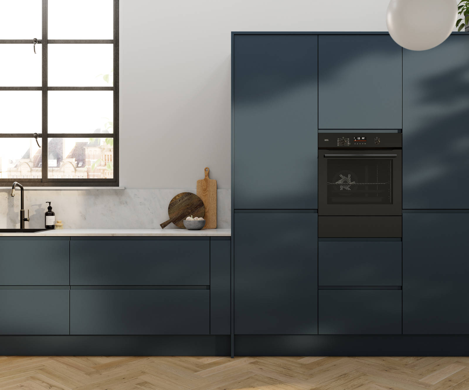Contemporary and minimalist handleless kitchen with J-Pull door in dark blue shade Mineral Blue, with marbled worktop and matching upstand, herringbone wood flooring.