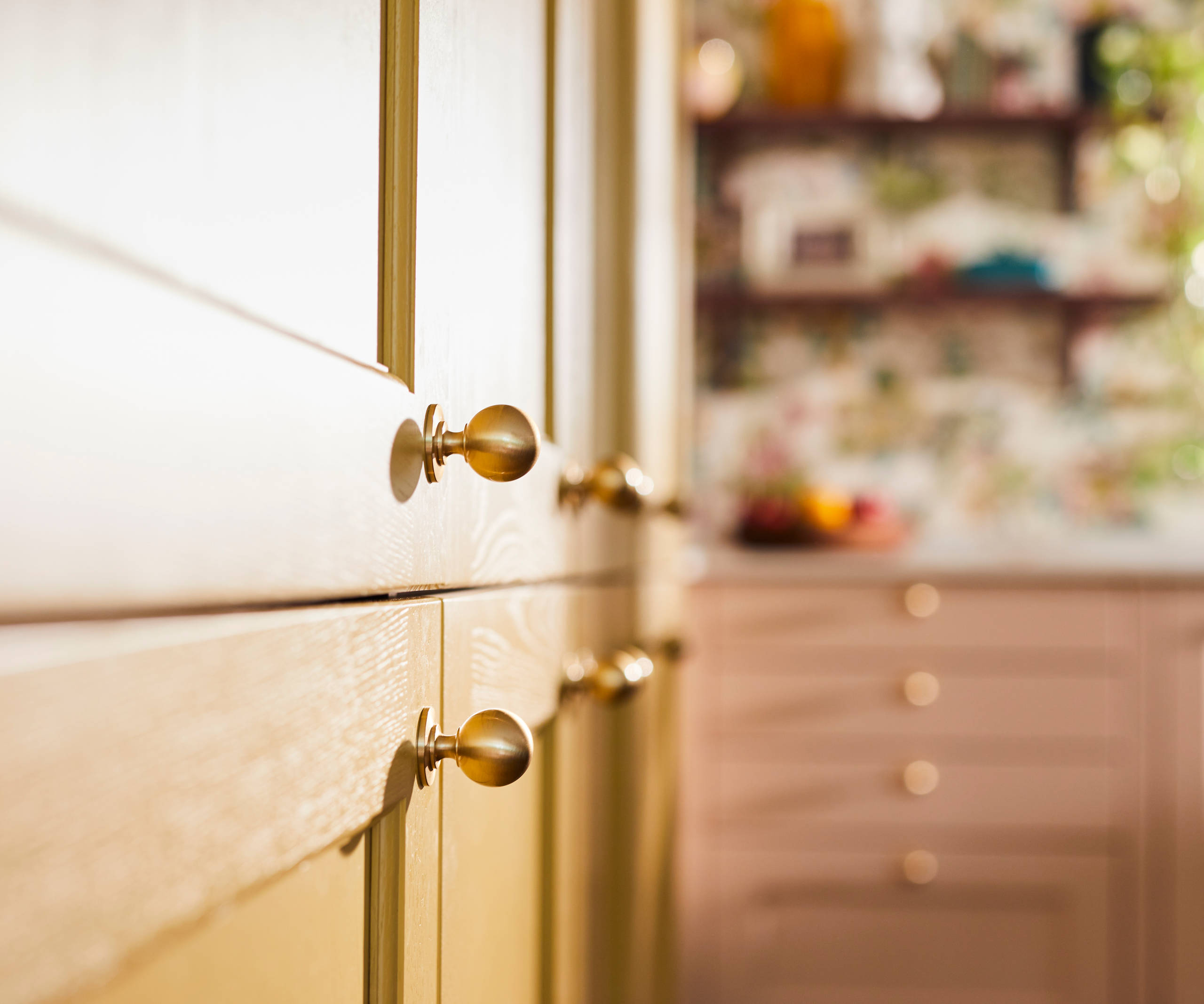 Close-up view of Douglas handles in Brushed Satin brass on Ludlow Harvest cabinets