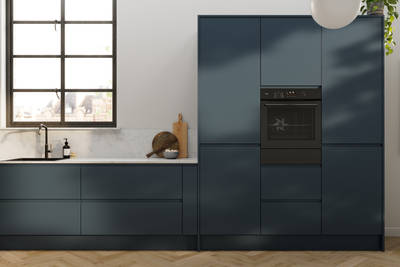 Contemporary and minimalist handleless kitchen with J-Pull door in dark blue shade Mineral Blue, with marbled worktop and matching upstand, herringbone wood flooring.