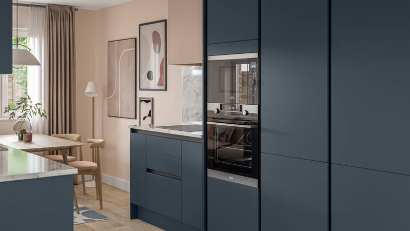 Handleless Integra Ascoli Mineral Blue, a dark blue kitchen with built-in ovens in tall cabinetry, an induction hob in white and grey marbled worktop with matching upstand.