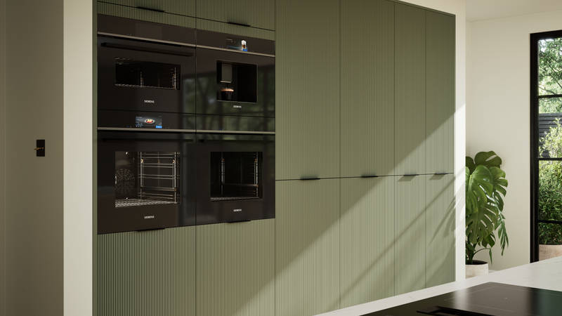 Green fluted kitchen fronts on tall cabinets with built-in appliances and black handles.